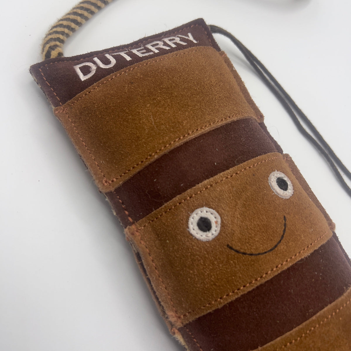 Brown boot-shaped dog toy with 'Duterry' written on it from green and wilds