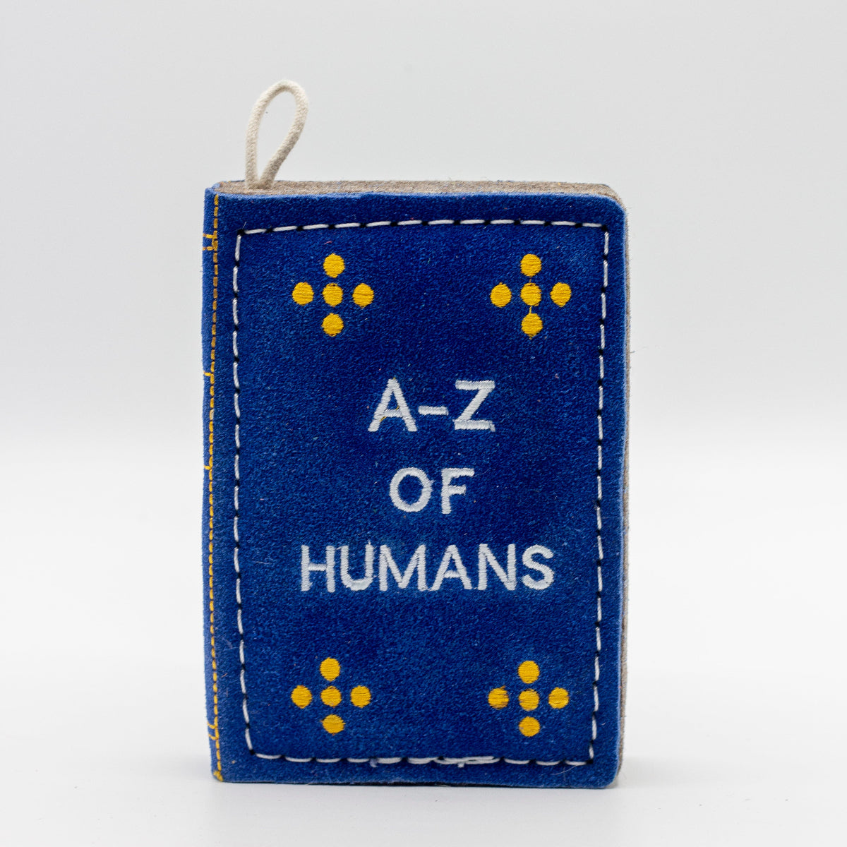 dog toy the shape of ablue book with 'A-Z of Humans' text