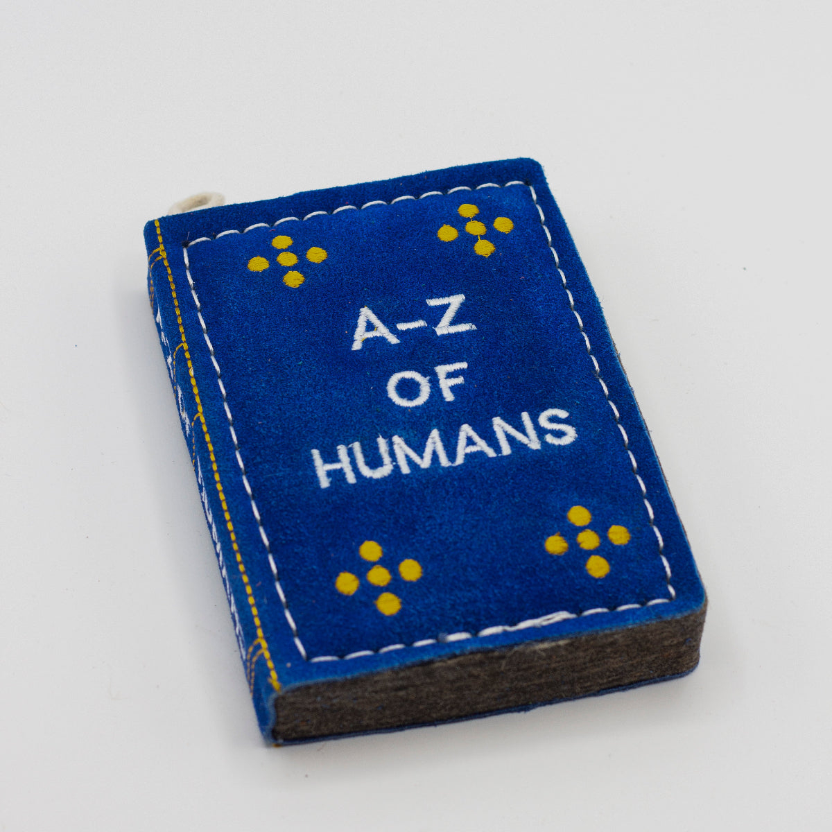 dog toy the shape of ablue book with 'A-Z of Humans' text