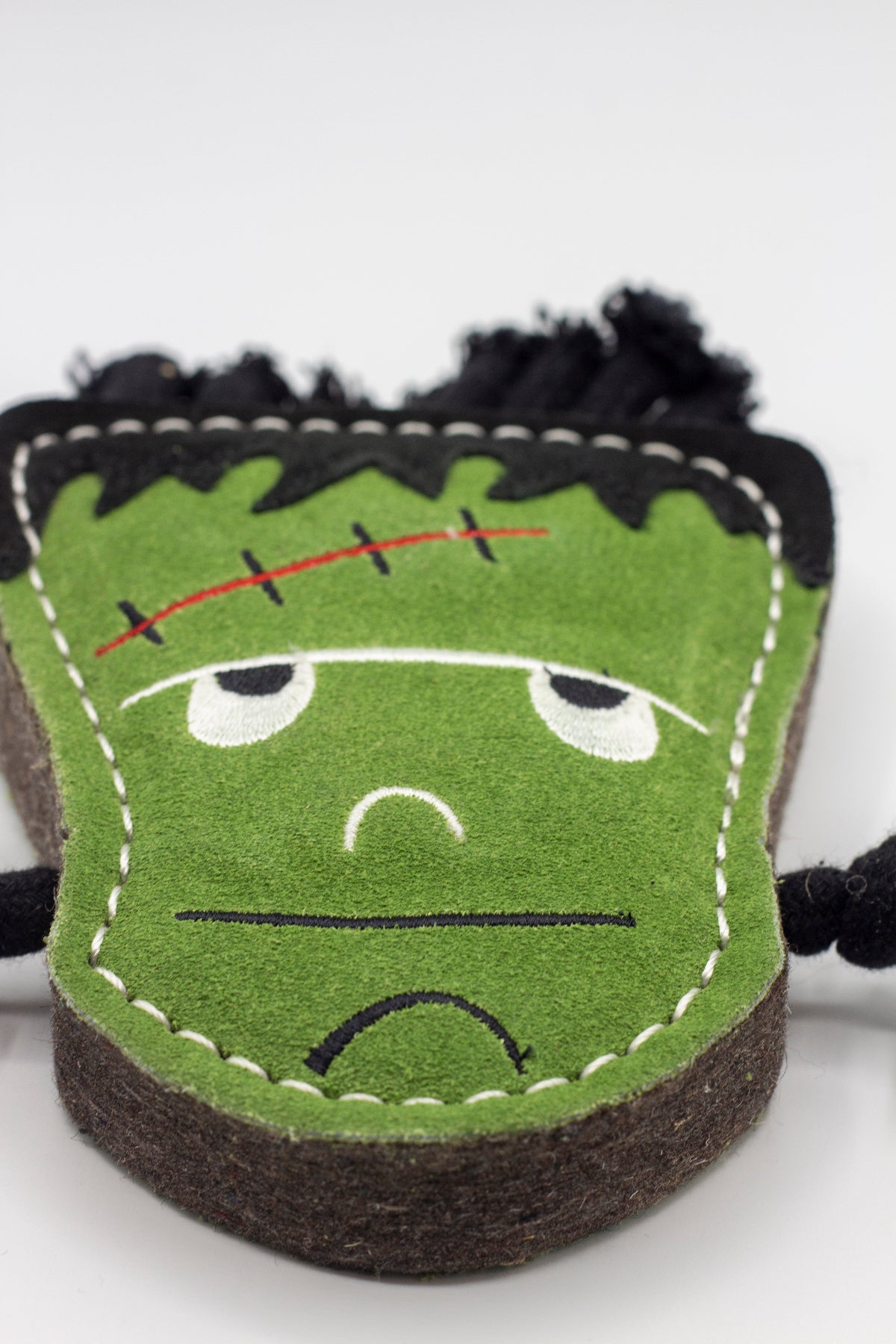 Halloween dog toy resembling a monster with black hair and stitch