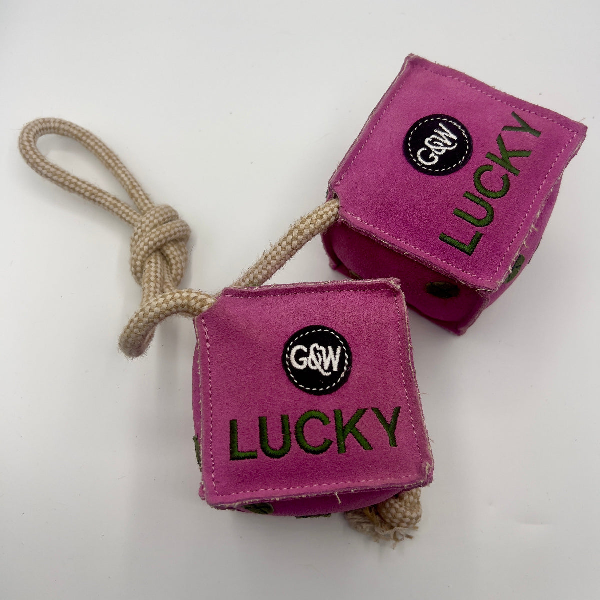 Pink dice-shaped horse and dog toy with green numbers and a rope