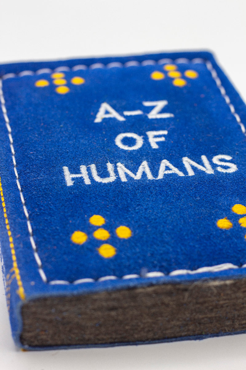 dog toy the shape of ablue book with 'A-Z of Humans' text 