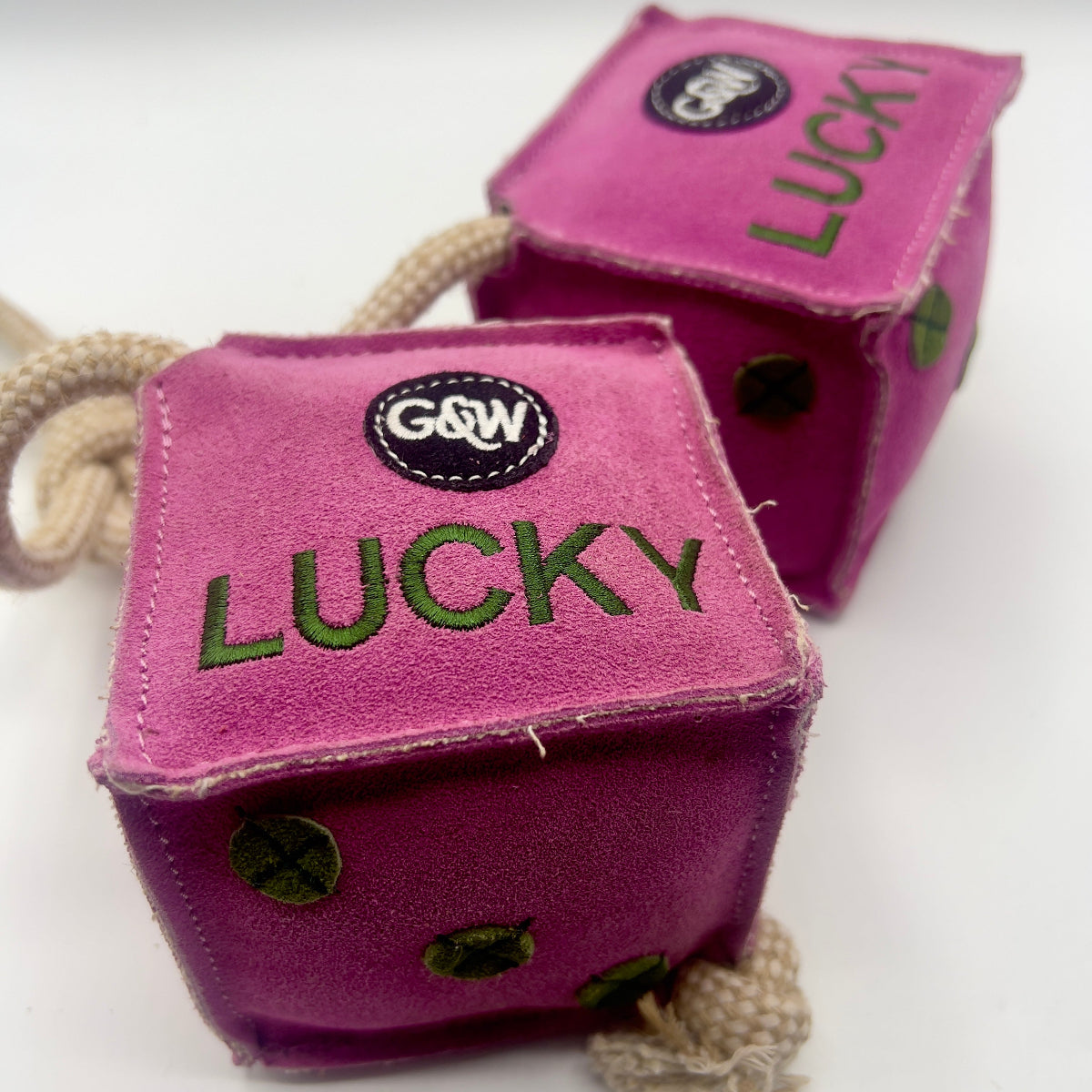Pink dice-shaped horse and dog toy with green numbers and a rope