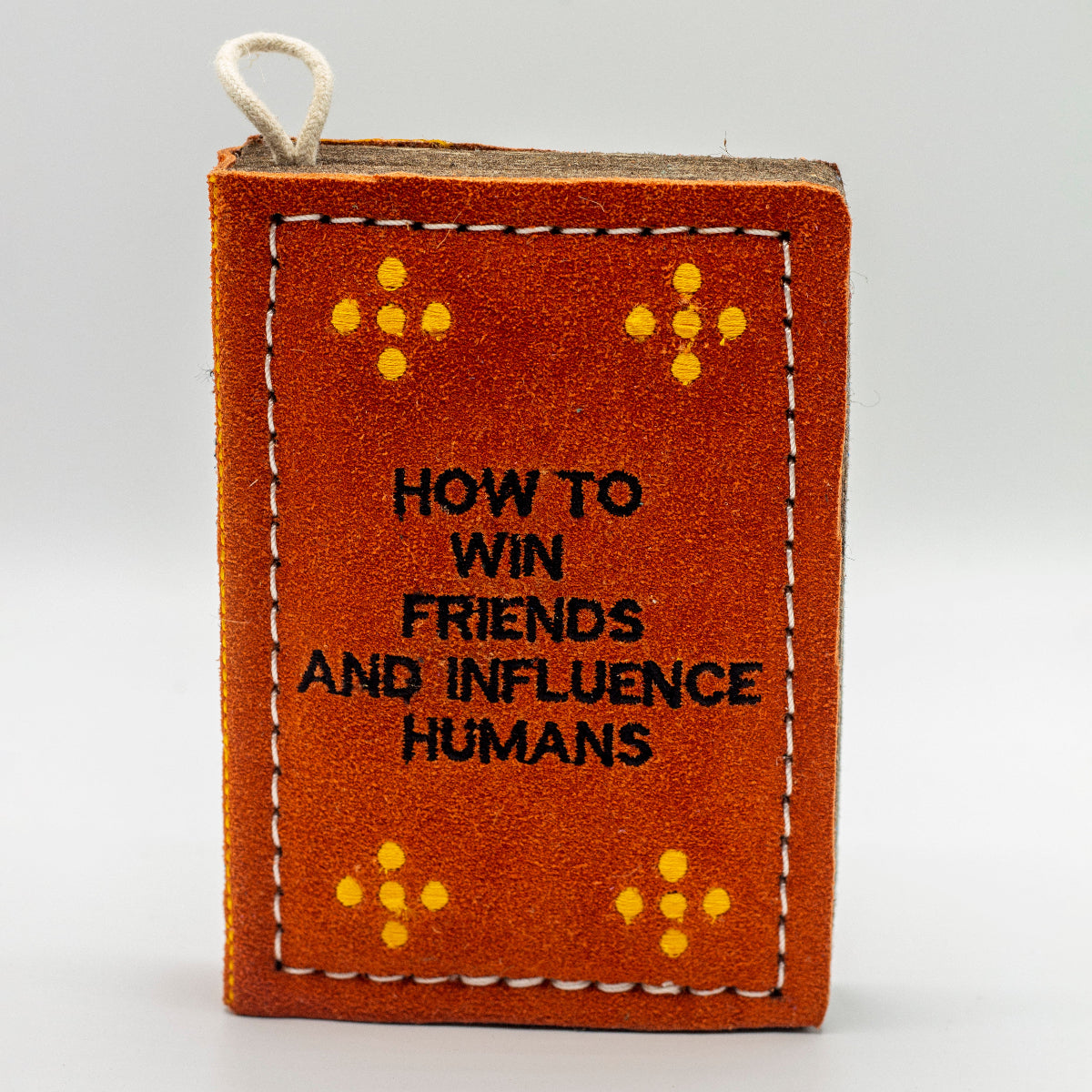 book-shaped dog toy with 'How to Win Friends and Influence Humans' text