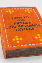 book-shaped dog toy with 'How to Win Friends and Influence Humans' text