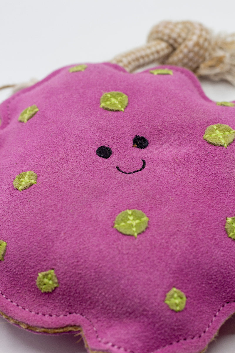 Pink suede dog toy with green spots and beige rope handles