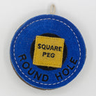 Blue circular dog toy labeled 'round hole' with a yellow square labeled 'Square Peg' inside