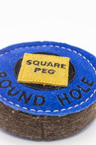 Blue circular dog toy labeled 'round hole' with a yellow square labeled 'Square Peg' inside